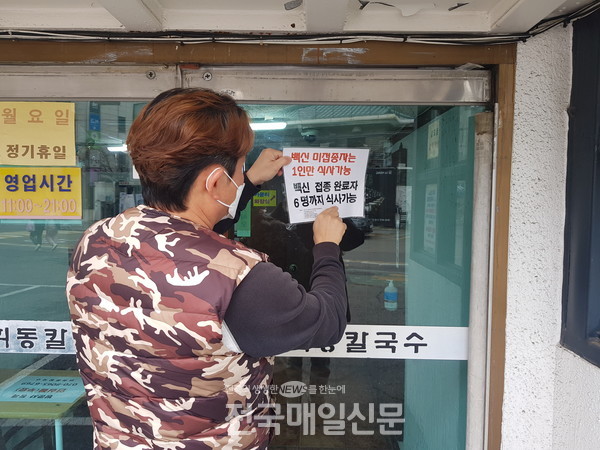 18일 서울 서대문구 연희동의 한 식당 직원이 거리두기 안내 표지를 교체하는 모습(사진제공/연합뉴스)