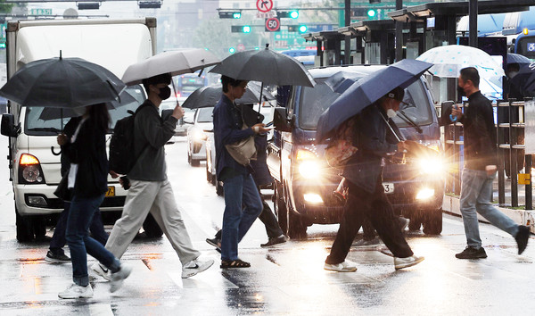 서울 시내에서 우산을 쓴 시민들이 횡단보도를 걷고 있다. 기상청은 이날 전국에 가끔 구름이 많겠고 소나기가 내리는 곳이 있다고 예보했다. 연합뉴스