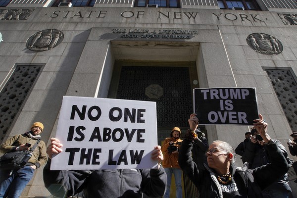 '성추행 입막음' 의혹을 받는 도널드 트럼프 전 미국 대통령에 반대하는 시민들이 20일(현지시간) 뉴욕 법원 앞에서 '트럼프는 끝났다', '법 위에 있는 사람은 없다'라고 쓴 손팻말을 들고 시위를 벌이고 있다. [뉴욕 AP=연합뉴스]