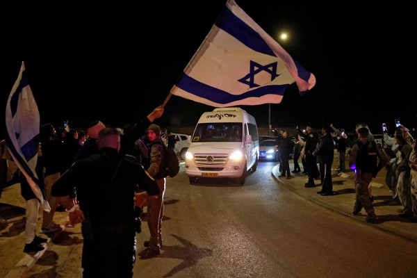 하마스에 납치된 뒤 풀려난 러시아인 인질 2명을 태운 차량이 이스라엘 오파킴을 지나는 가운데 29일(현지시간) 한 남성이 이스라엘 국기를 흔들고 있다. 이스라엘군은 하마스가 러시아인 인질 2명을 석방했다. [이스라엘 AFP=연합뉴스]