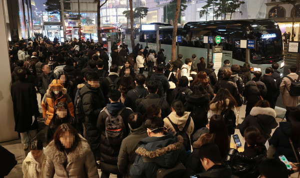 5일 저녁 서울 중구 명동에서 퇴근길 시민들이 버스를 기다리고 있다. 서울시는 명동입구 광역버스 정류소에 노선 표시 안내판(줄서기 표지판)을 설치한 뒤 오히려 퇴근길 차량 정체가 심해지자 표지판 운영을 이달 31일까지 유예하기로 했다. [연합뉴스]