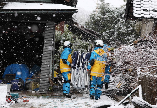 7일 지진 피해 지역인 일본 이시카와현 스즈시에 많은 눈이 내리는 가운데 경찰들이 실종자 수색 작업을 벌이고 있다. 새해 첫날 노토반도를 강타한 규모 7.6 지진으로 최소 120명이 숨진 것으로 집계됐다. [스즈 EPA·지지=연합뉴스]