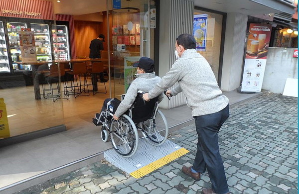 휠체어를 이용하는 주민이 경사로를 통해 가게 입구로 들어가고 있다. [성동구 제공]