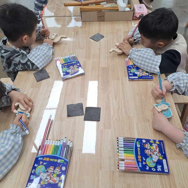 어린이들이 천왕산 목공체험장에서 만든 작품에 색칠을 하고 있다. [구로구 제공]