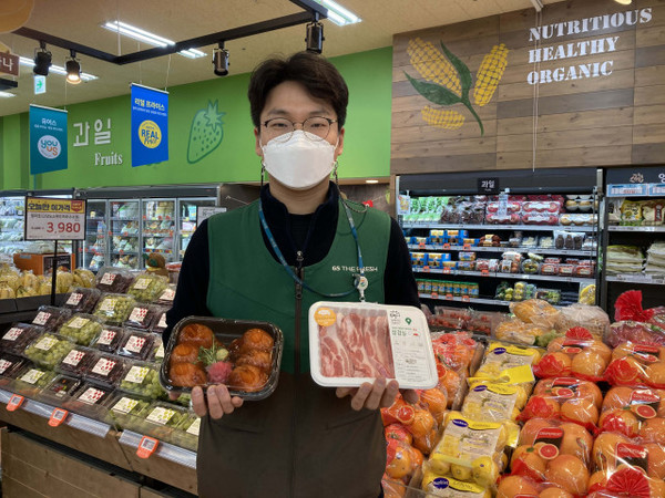 GS수퍼마켓에서 직원이 배달 인기 상품 삼겹살과 대왕연어초밥을 들고 있다. [GS수퍼마켓 제공]
